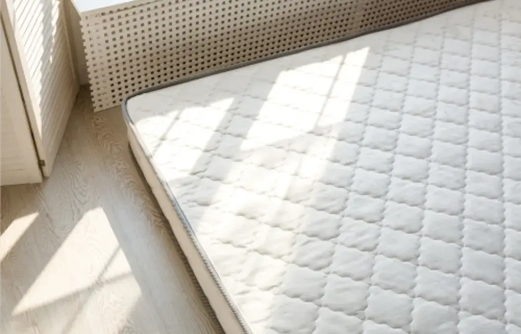 Clean and fresh mattress in a sunlit bedroom.