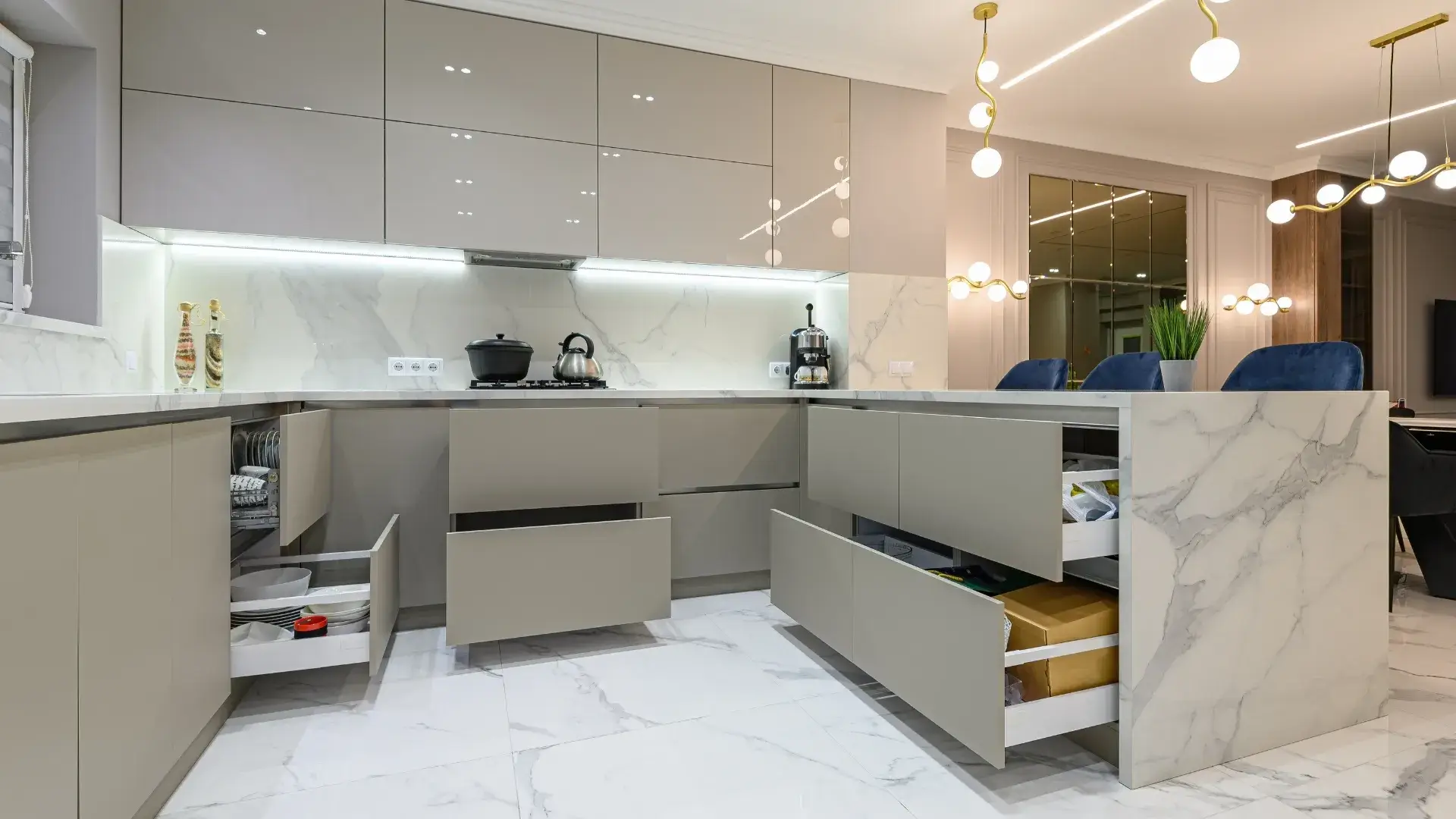 Modern kitchen with sleek cabinetry, marble countertops and open drawers showcasing organized storage.