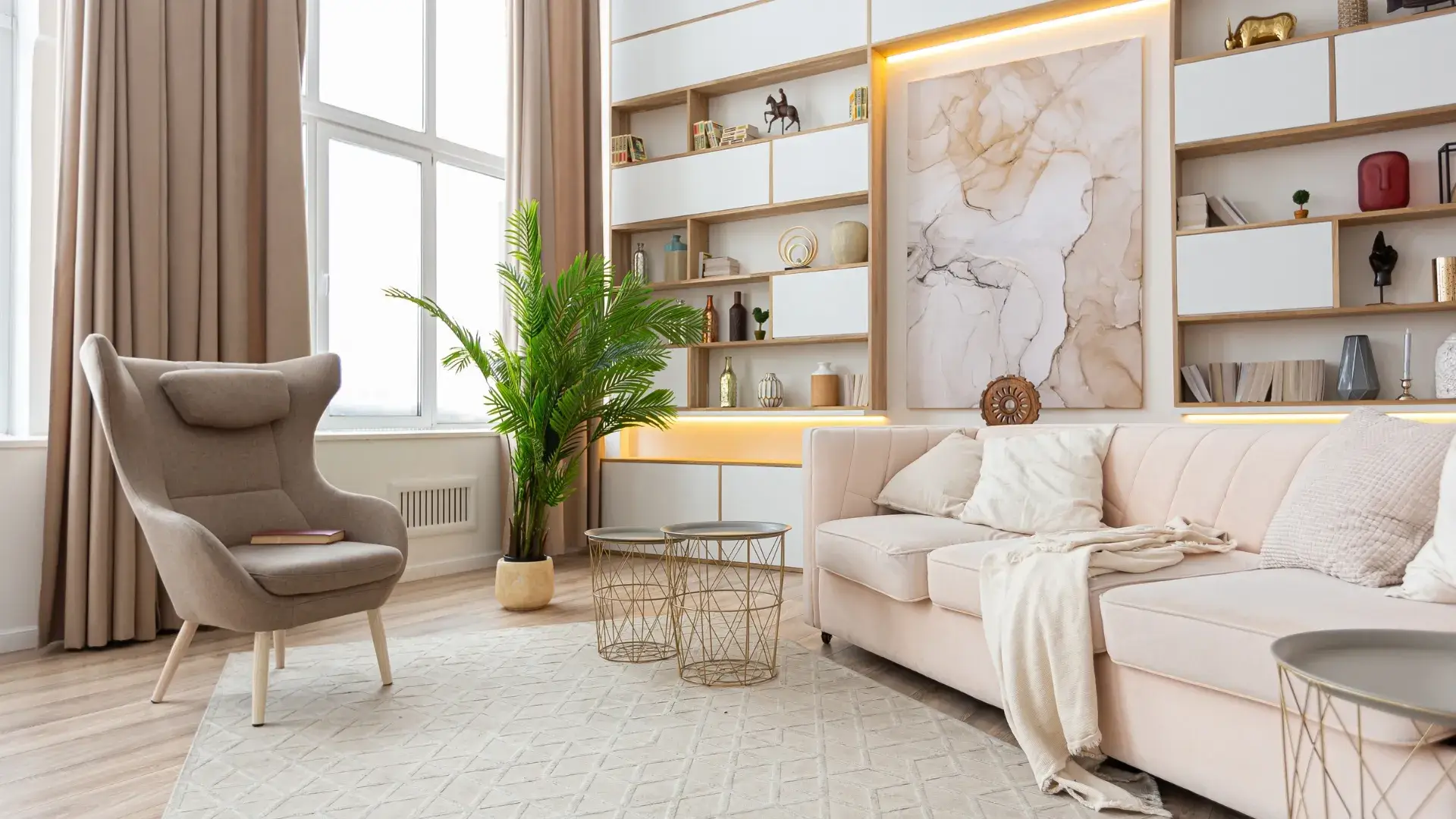 Modern living room with beige furniture, decorative shelving and soft lighting.