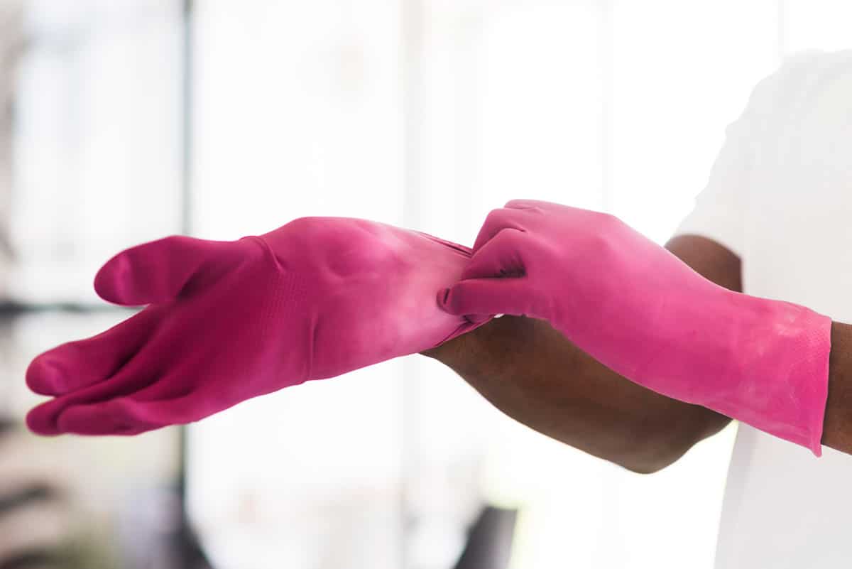 Person putting on pink gloves for free cleaning for cancer patients.