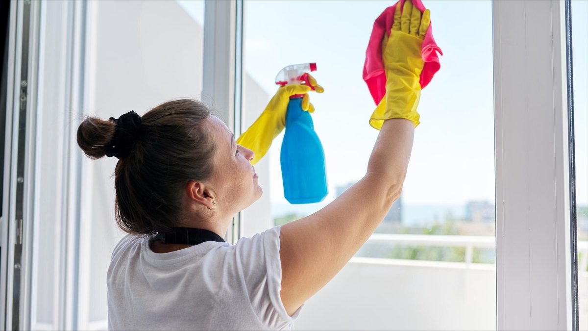 Woman cleaning window with spray bottle