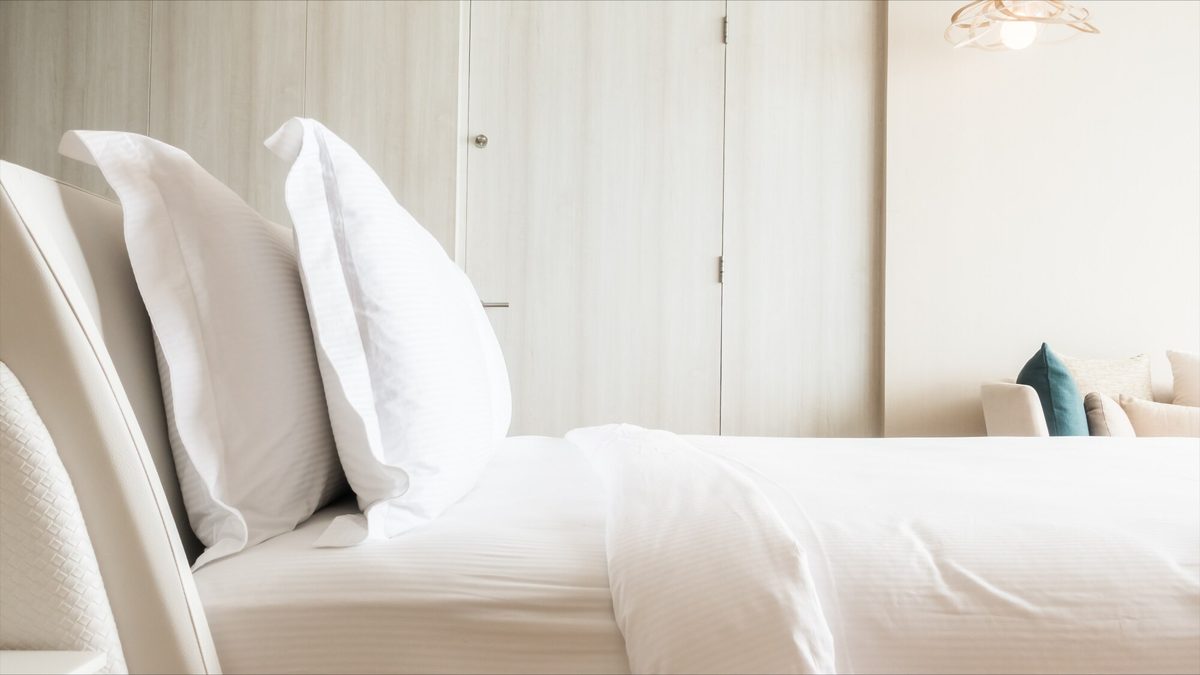 White hotel bed with pillows and wardrobe