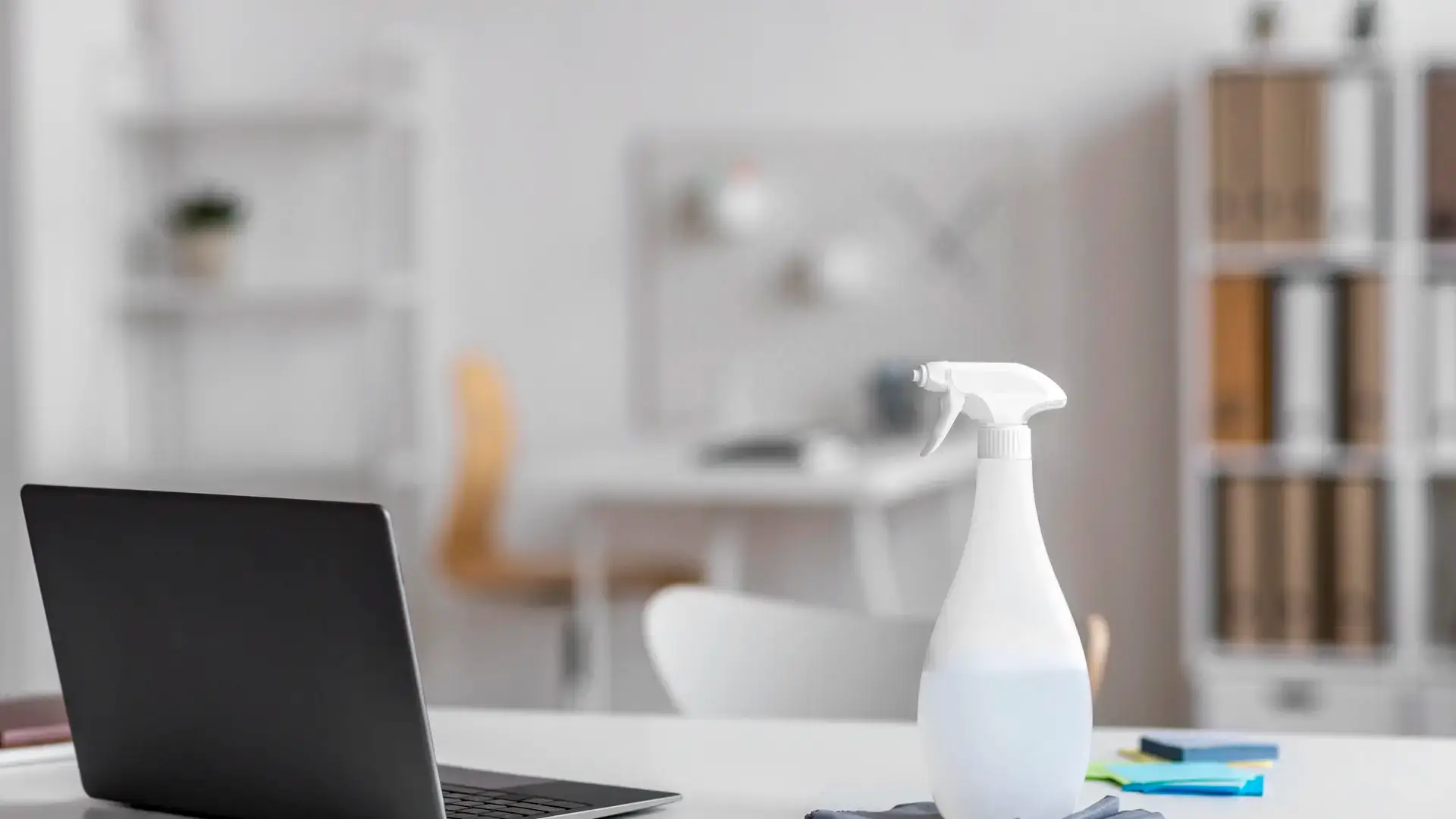 Disinfecting spray bottle beside laptop on office desk