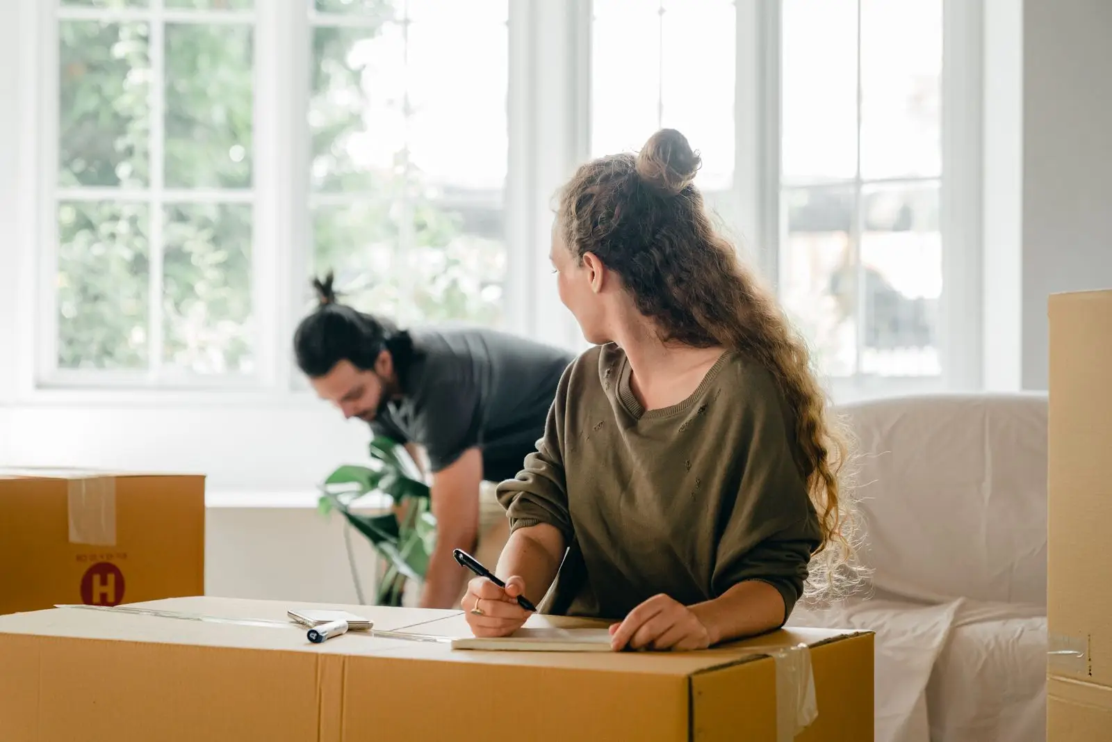 Adult children packing moving boxes and making a list while downsizing a parent home in Allen, Texas