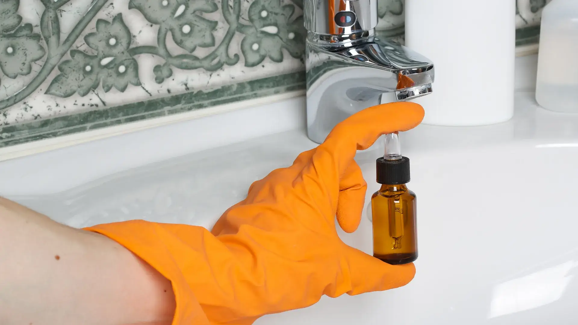 Gloved hand cleaning bathroom sink faucet