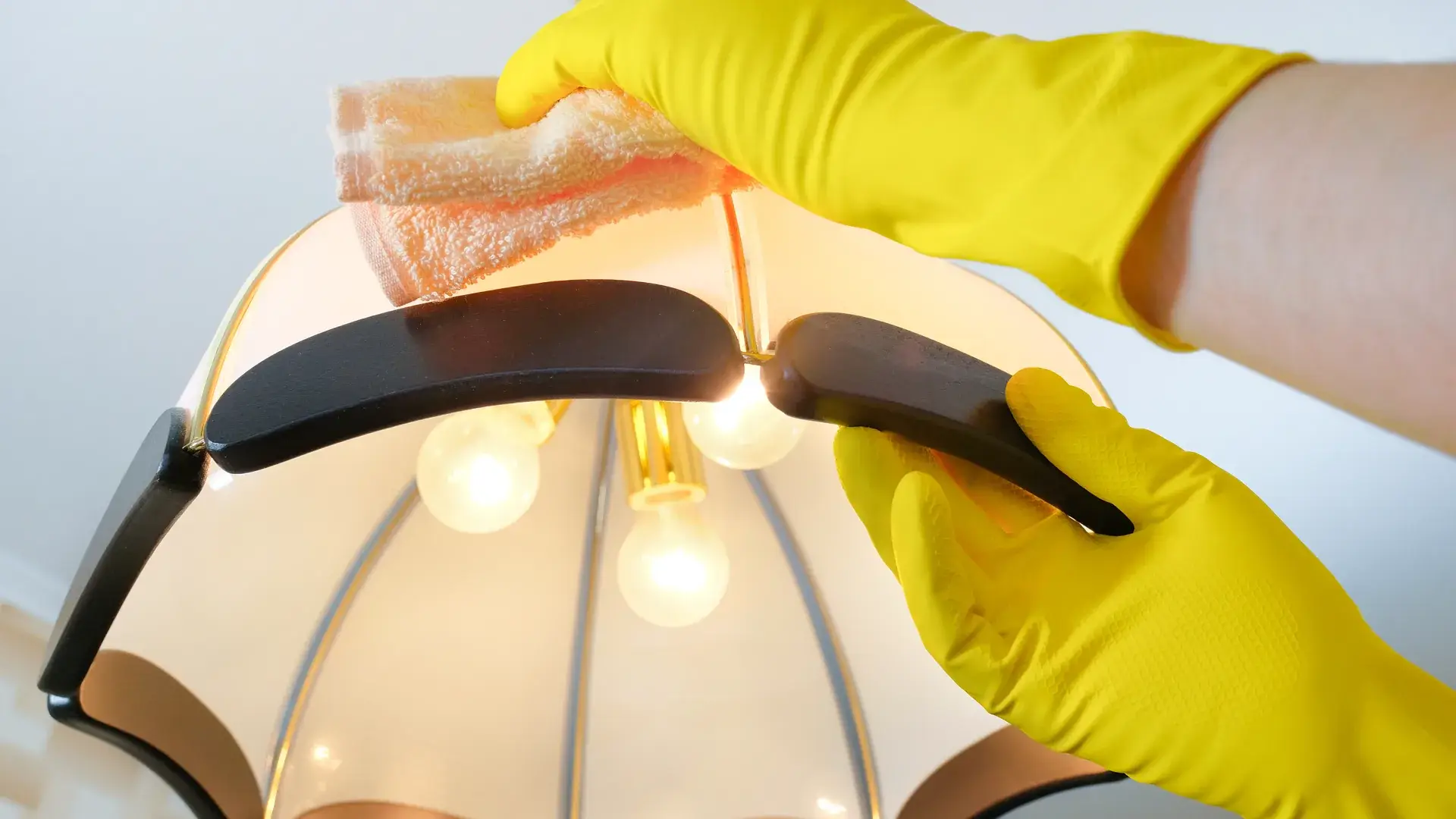 Gloved hands wiping dust off a chandelier