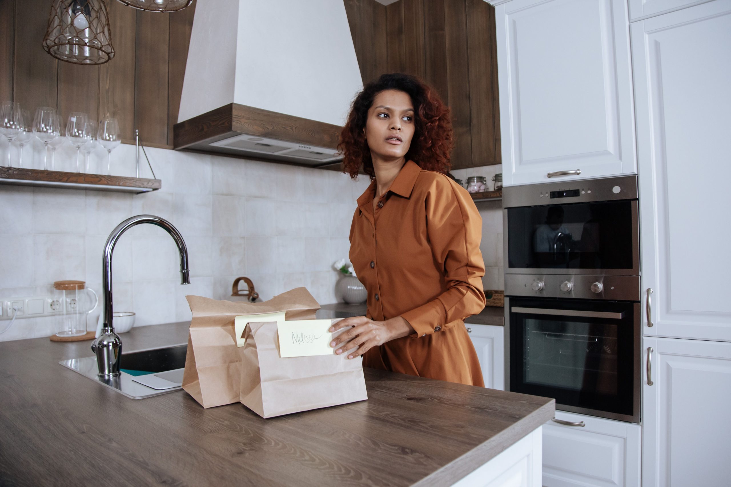 A parent packing paper lunch bags on a bright kitchen counter
