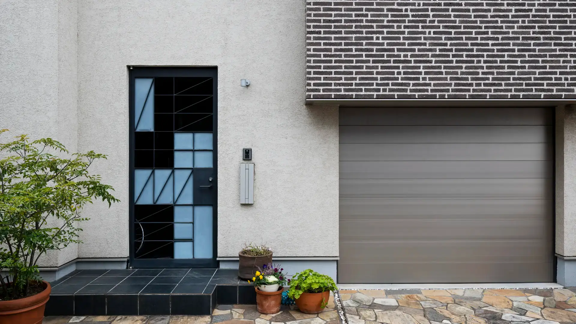 Modern house entrance with garage and potted plants