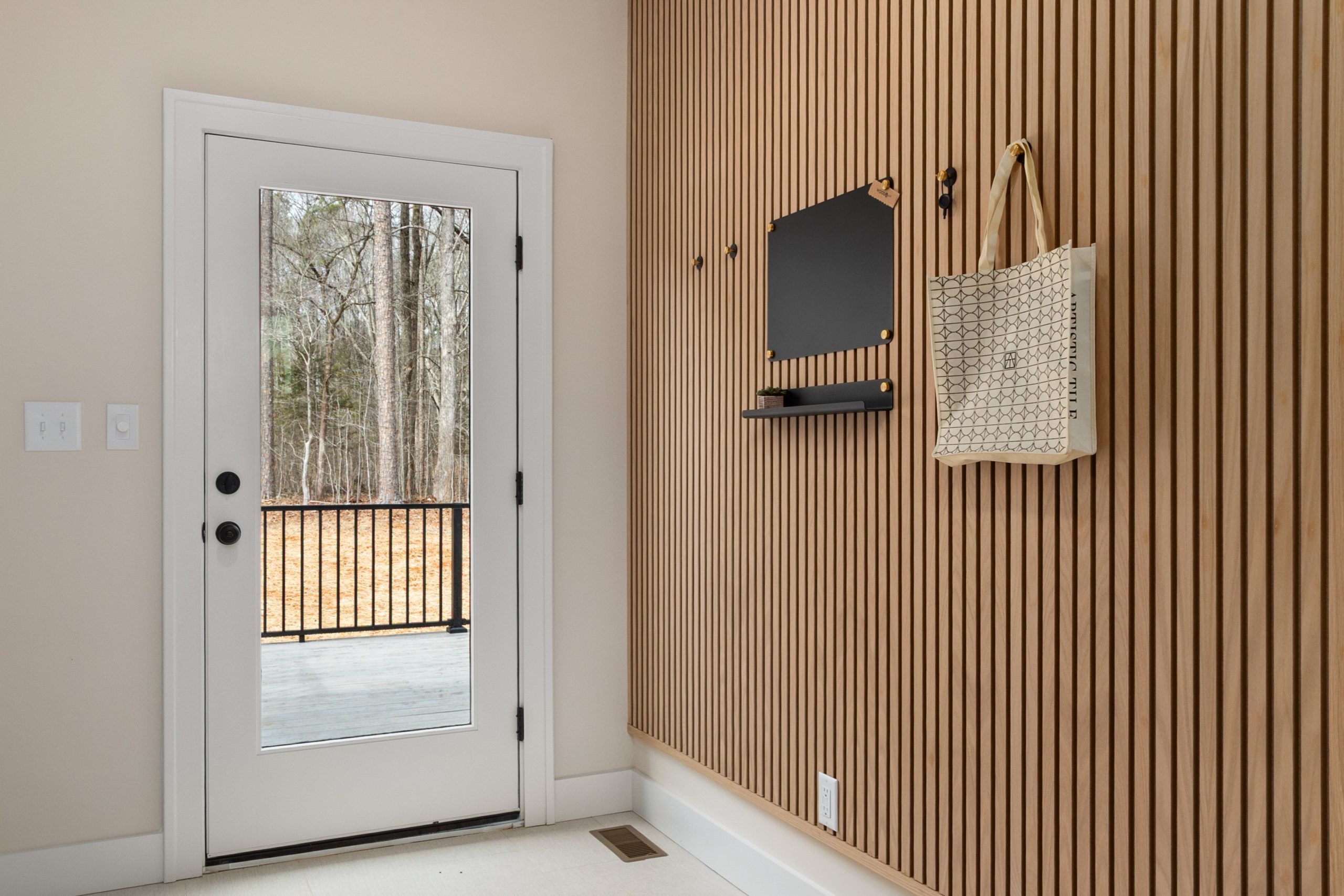 Bright modern mudroom entryway with wood paneling and glass door in a Prosper TX home