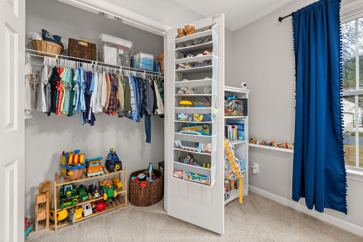 A neatly organized children's closet featuring clothes, toys, and storage solutions