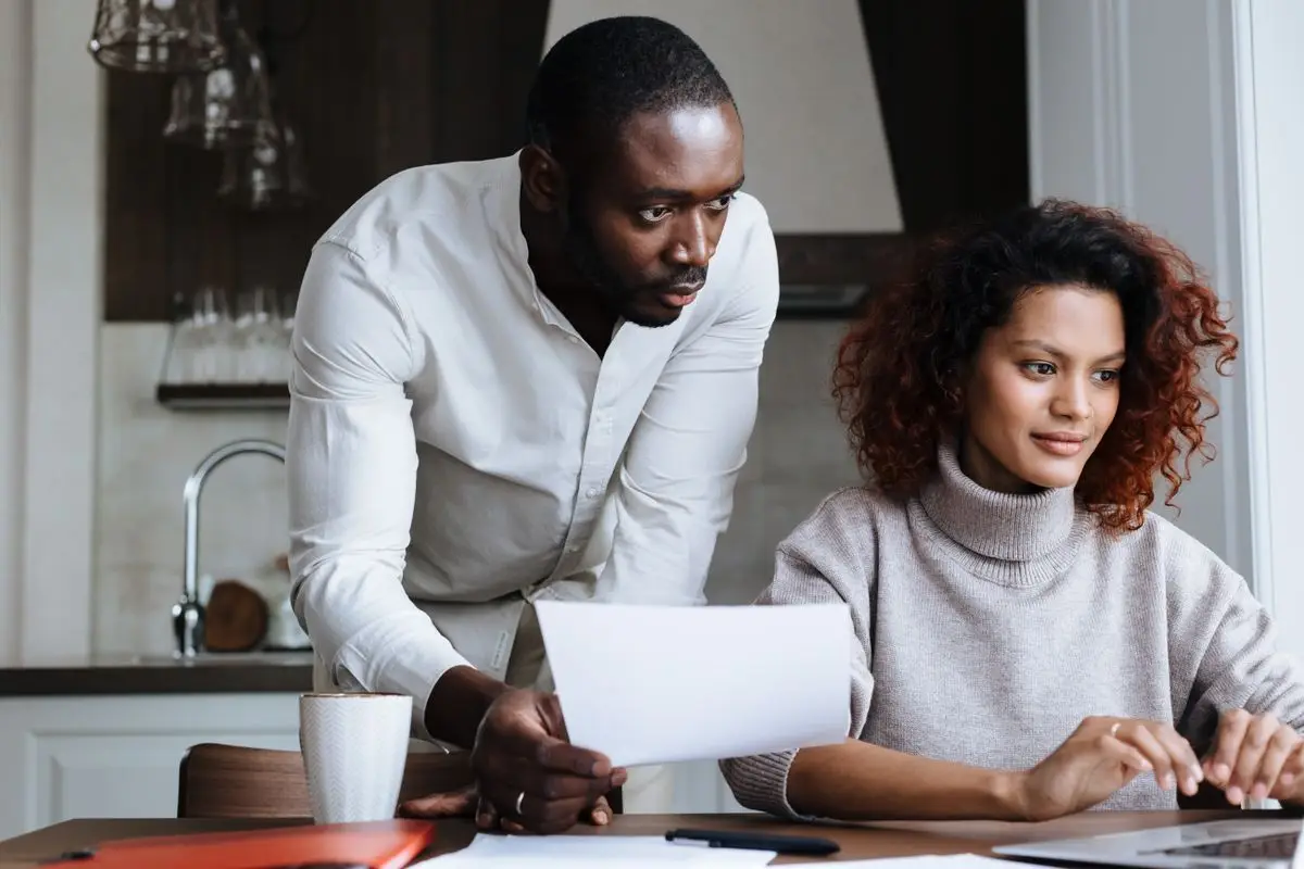 Two parents working together at a laptop in a bright, organized home kitchen