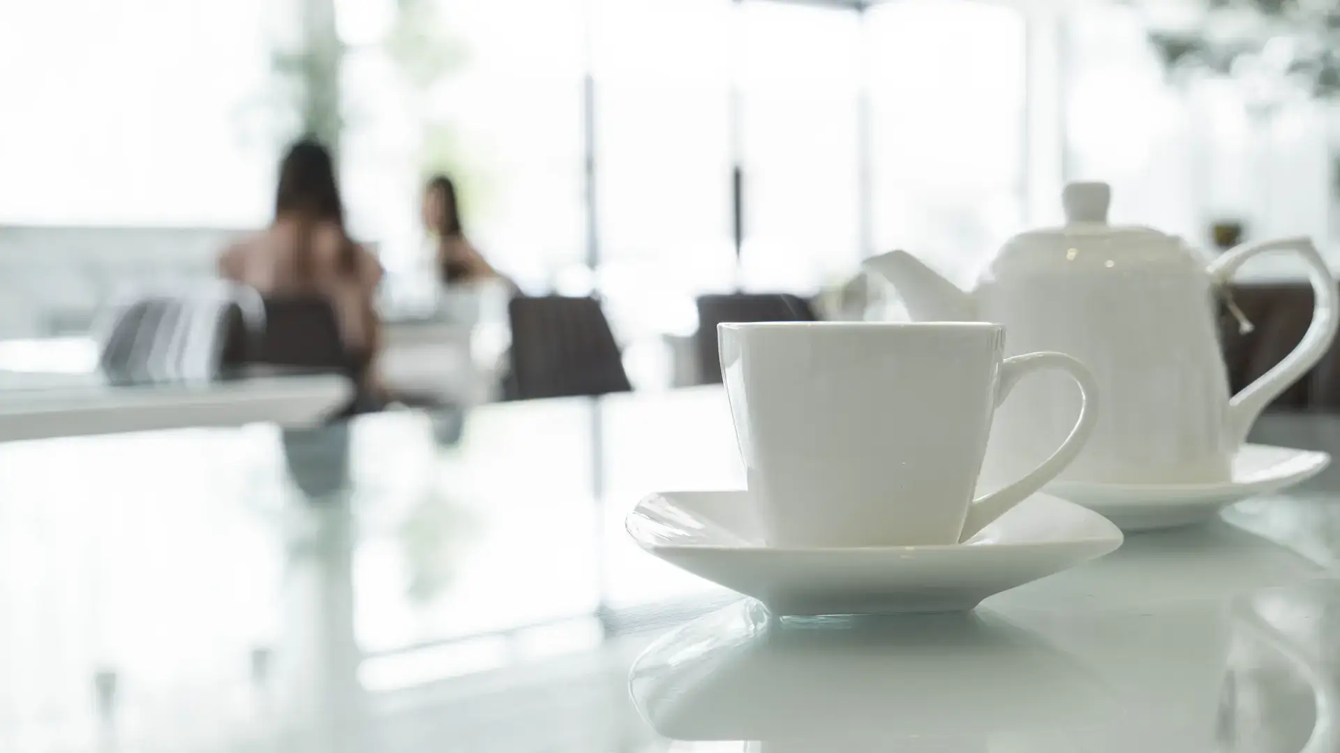 Teacup and teapot on glass table in cafe