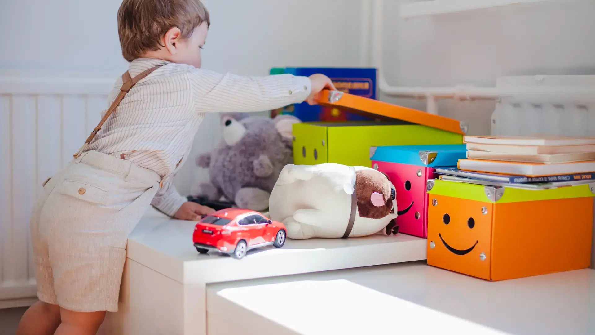 Toddler opening colorful toy storage box