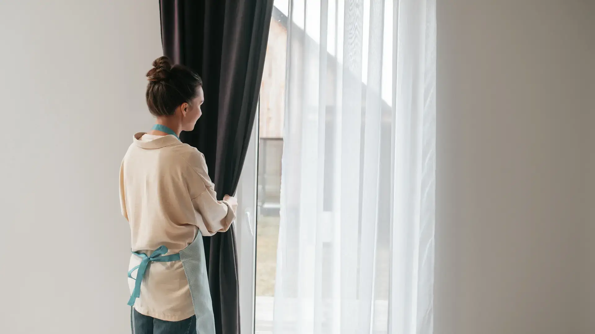 Woman opening curtains near bright window