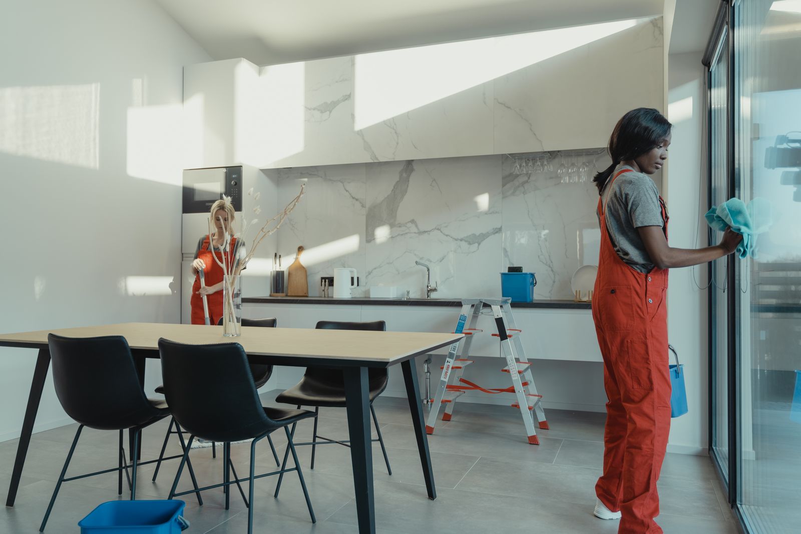 Two professional cleaners working in order through a bright modern kitchen in McKinney TX
