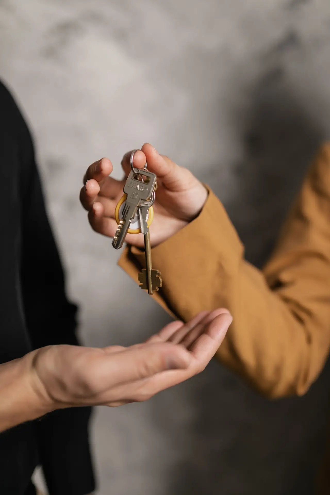 Hands exchanging house keys representing trust with a background checked housekeeper in Park Cities TX