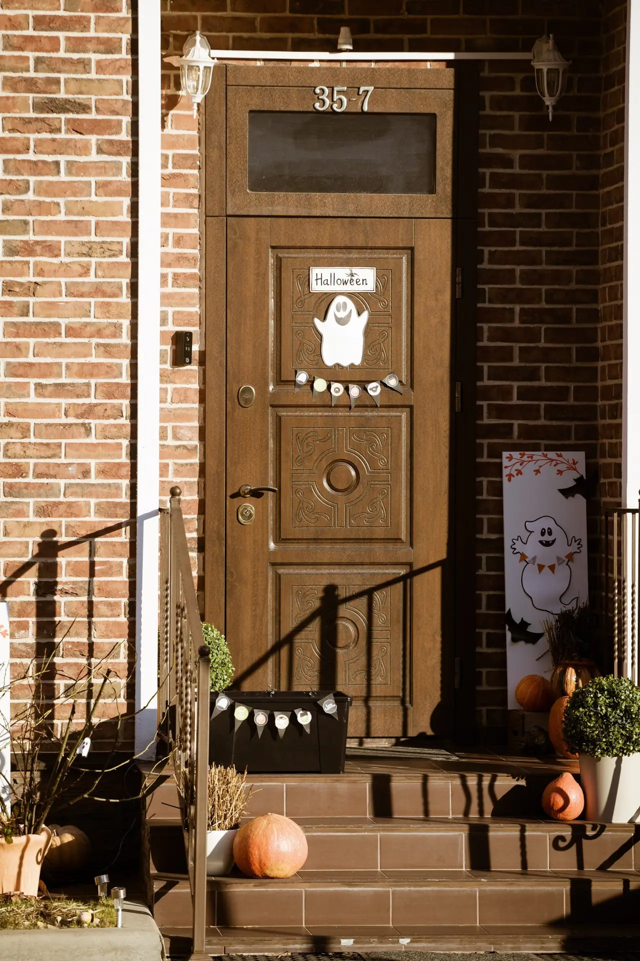 Brick home front door decorated with pumpkins and a ghost for Halloween in Frisco TX